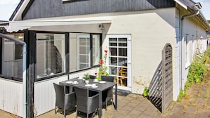 Ein zweistöckiges Haus mit Balkon, einer Essecke inklusive Tisch und Stühlen sowie einer Garage.