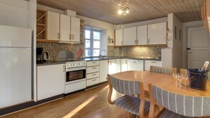 Eine moderne Küche mit weißen Schränken, einem Holzespeisetisch mit gestreiften Stühlen und einer Arbeitswand aus Stein.