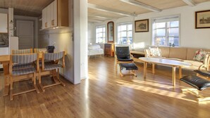 Uma sala de estar ampla com piso de madeira, uma mesa de jantar e opções de assento.