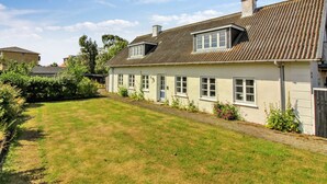 Ein zweigeschossiges Haus mit einem geneigten Dach, einer Veranda und einem gepflegten Rasen.