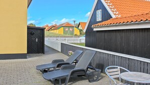 A courtyard with a wooden fence, a yellow building, a blue building with a tiled roof, and outdoor furniture. - "Borka" - 150m from the sea by Interhome (Skagen)