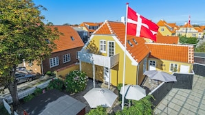 Zona residencial con casas que tienen techos de tejas rojas y una destacada bandera danesa.