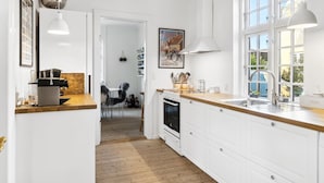 Una cocina moderna con armarios blancos, encimera de madera y un amplio ventanal.