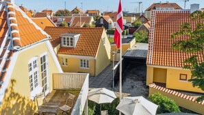 Un patio con edificios amarillos, una bandera y vistas del entorno.