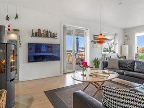 A modern living room with a large TV, a sofa, a coffee table, and a fireplace.