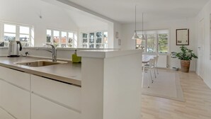 A modern kitchen with a large island, a sink, and a dining area with a table and chairs. - "Janes" - 400m from the sea by Interhome (Skagen)