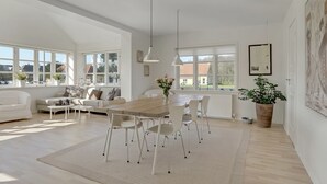 A spacious living room with a large window, a dining area with a wooden table and white chairs, and a white sofa with cushions. - "Janes" - 400m from the sea by Interhome (Skagen)