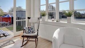 A bright room with large windows, a rocking chair, a white armchair, and a view of the backyard. - "Janes" - 400m from the sea by Interhome (Skagen)