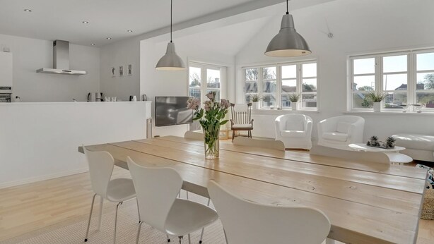 A modern kitchen with white cabinetry, a wooden dining table, and pendant lighting. - "Janes" - 400m from the sea by Interhome (Skagen)