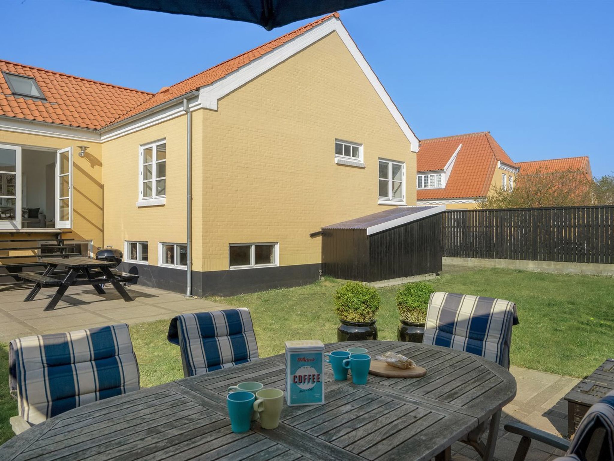 A patio area with a wooden table, chairs, and a barbecue grill.