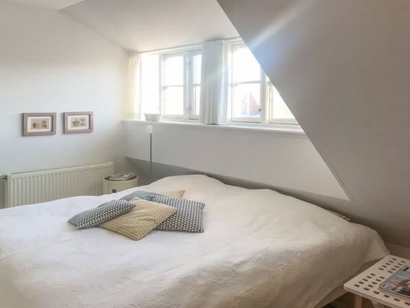 A bedroom with a large bed, a window, and a radiator.