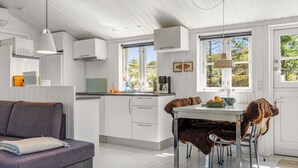A modern kitchen with white cabinetry, a dining area with a table and chairs, and a cozy seating area with a sofa. - "Thorkil" - 800m from the sea by Interhome (Skagen)