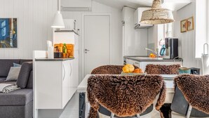 A modern kitchen with white cabinets, a dining area with a table and chairs, and a grey sofa. - "Thorkil" - 800m from the sea by Interhome (Skagen)