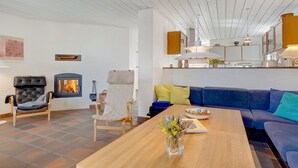 A modern living room with a fireplace, a sofa, a coffee table, and a dining area.