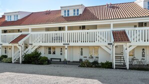 Un edifici de dues plantes amb façana blanca, múltiples balcons i un camí d'accés de grava.