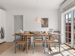 Ein Essbereich mit einem Holztisch, blauen Stühlen, einer Hängelampe und einem Poster an der Wand.