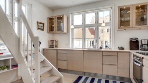 A modern kitchen with wooden cabinets, a built-in stove, and a large window.