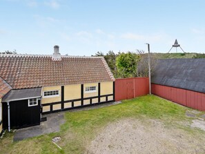 Ein zweigeschossiges Haus mit einem Ziegeldach, einer kleinen angebauten Garage und einem roten Zaun.