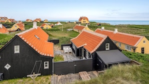 A coastal village with traditional houses, a wooden dock, and a view of the sea.
