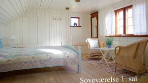 A bedroom with a bed, a chair, a table, and a window.