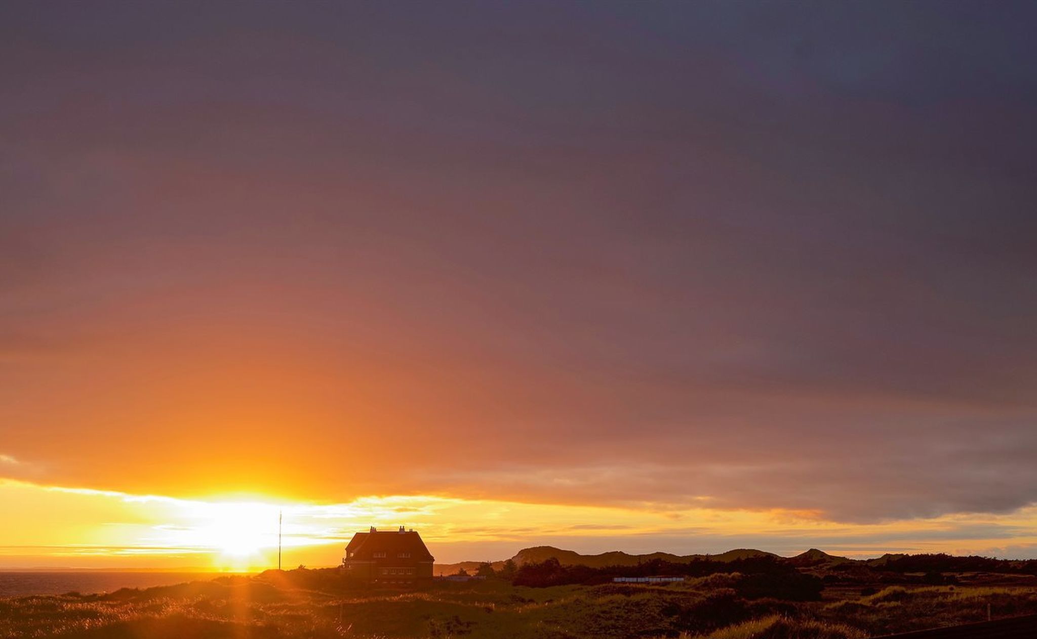 Ein Sonnenuntergang über einer Landschaft mit einem Haus namens Solnedgang.