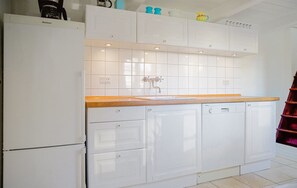 Una cocina con armarios blancos, encimera de madera y lavavajillas.