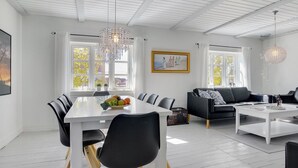 Amplia sala de estar con comedor, techo blanco, ventanas grandes y muebles modernos.