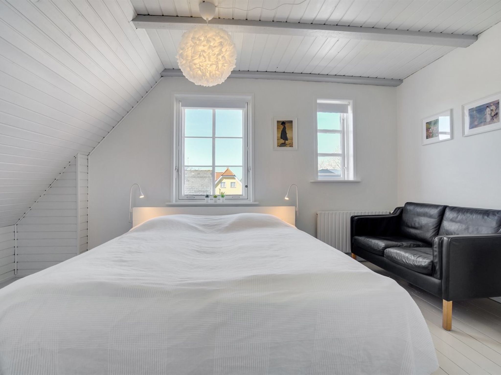 Una camera da letto con un letto grande, un divano in pelle nera e due finestre.