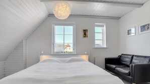 Un dormitorio con una cama grande, un sofá de cuero negro y dos ventanas.