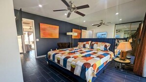 A bedroom with a large bed, ceiling fans, a mirror, and a view of the outside. - PalmSpringsBNB - Renovated 1Bd with Amazing Views (Palm Springs)