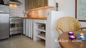 Une cuisine moderne dotée d’appareils électroménagers en acier inoxydable, de meubles en bois et d’un coin repas avec une chaise en osier et une table.