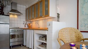 A modern kitchen with stainless steel appliances, wooden cabinets, and a dining area with a woven chair and a table. - "Elle" - 50m from the sea by Interhome (Skagen)