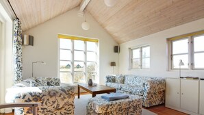 Una sala de estar acogedora con techo alto, un conjunto de sofás, una mesita y un armario.