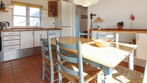 Cocina compacta con una mesa y sillas de madera, una lámpara colgante y una ventana con vistas.