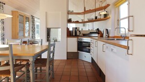 Una cocina moderna con una mesa y sillas de madera, horno empotrado y una ventana.