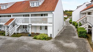 Eine Reihe weißer Gebäude mit roten Ziegeldächern und weißen Balkonen, die entlang eines Kieswegs angeordnet sind.