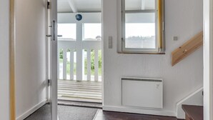 Ein Flur mit einer weißen Tür, die zu einem Balkon mit weißer Brüstung führt.