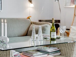 A glass-top table with a wine bottle, two candles, and a vase with a flower.