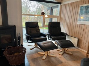 A room with two black leather chairs and a matching ottoman, a fireplace, and a wooden floor. - "Eldmar" - 500m from the sea by Interhome (Ålbæk)