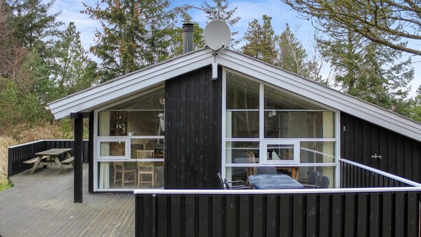 A cabin with a large deck, a satellite dish, and a view of the surrounding forest.