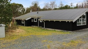 A black building with a sloped roof and a gravel driveway.