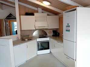 A compact kitchen with white cabinets, a stainless steel stove, a built-in oven, a sink, and a white refrigerator.