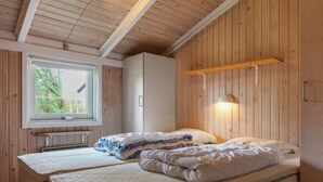 Un dormitorio con dos camas, una ventana, un armario y una lámpara de pared.