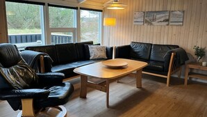 A modern living room with a black leather sofa, a wooden coffee table, and a black leather chair.