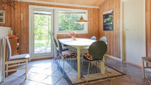 Een kamer met houten lambrisering, een ronde tafel, stoelen en een raam.