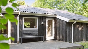 Een rustieke houten hut met een veranda, een bank en een deur.