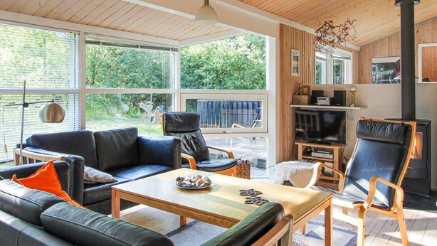 Een moderne woonkamer met een open haard, leren banken en een eettafel.