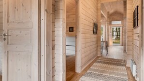 A wooden interior with a hallway leading to a dining area and a view of trees.