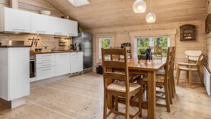 A modern kitchen with white cabinets, a stainless steel refrigerator, and a dining area with wooden chairs and a table.