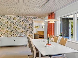 A modern dining area with a white table, chairs, and a decorative wall with a floral pattern. - "Gorm" - 300m from the sea by Interhome (Jerup)